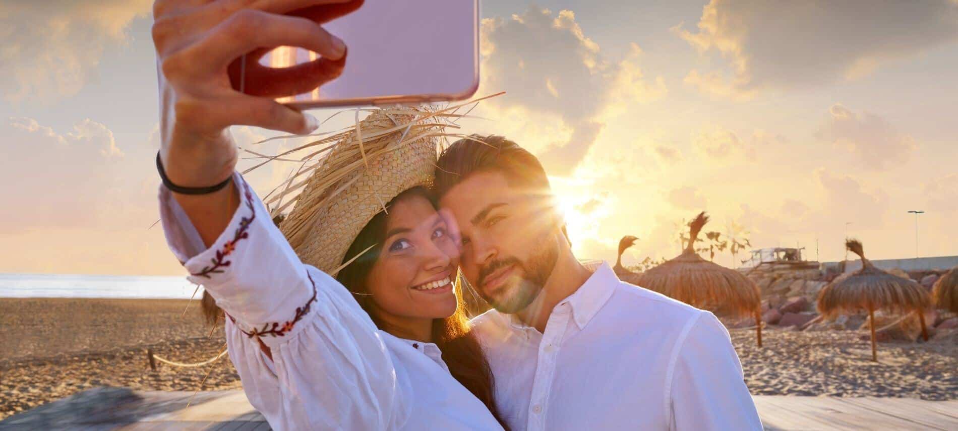 couple taking a selfie on the beach at sunset